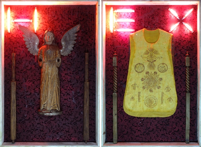 Norberto Roldan, Hex, 2015, Salvaged 17th century wooden statue of Archangel Raphael and other architectural debris from a typhoon damaged church from Southern Philippines, 18th century Catholic vestment newly hand-embroidered with Philippine millenarian symbols and prayers, metal amulet, vintage damask fabric, beeswax and lighting fixture on panel,  183 x 122 cm each panel / 183 x 244 cm, diptych, ROLD0011 